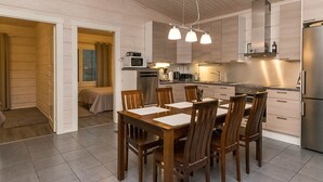 A modern kitchen with a dining area, featuring a central island, built-in appliances, and pendant lighting. - Villa mari by Interhome (Pertunmaa)