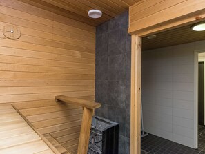 A wooden sauna room with a bench, a sauna door, and a ventilation system.