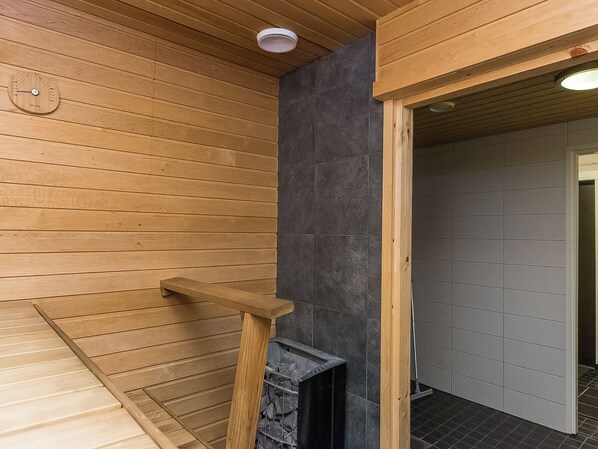 A wooden sauna room with a bench, a sauna door, and a ventilation system.