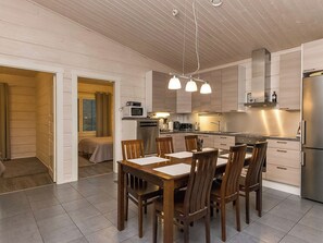 Cocina moderna con comedor, que incluye una isla central, iluminación colgante y un microondas a la vista.