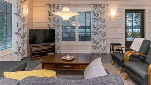 A living room with a television, a coffee table, a sofa, and curtains with a leaf pattern. - Villa mari by Interhome (Pertunmaa)