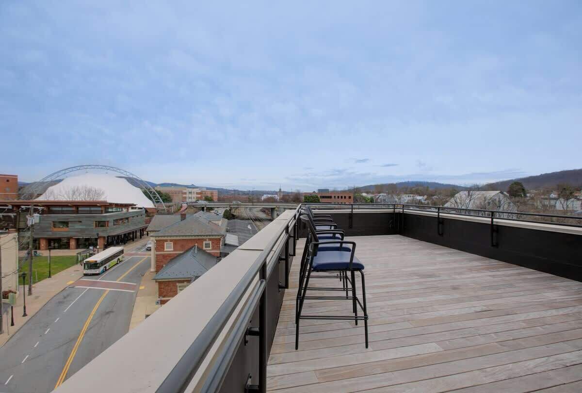 A rooftop terrace with a view of a cityscape, including a bus and buildings.