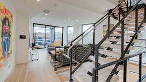 A modern interior with a staircase, large windows, and a city view. - Downtown C'ville Luxury w/ Rooftop Terrace (Charlottesville)