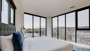 A bedroom with a large bed, a view of the city, and a window with a black frame. - Downtown C'ville Luxury w/ Rooftop Terrace (Charlottesville)