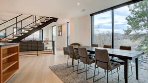 A modern interior with a staircase, dining area, and large windows offering a view. - Downtown C'ville Luxury w/ Rooftop Terrace (Charlottesville)
