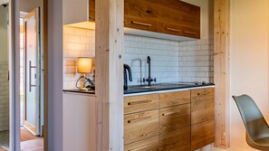 A modern kitchen with wooden cabinets, a black faucet, and a white tiled backsplash.