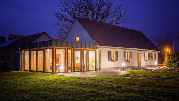 Une maison moderne avec une grande entrée en verre, une allée pavée et une pelouse bien entretenue.