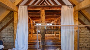 Un intérieur rustique en bois, avec des poutres apparentes, un escalier et une rampe en métal.