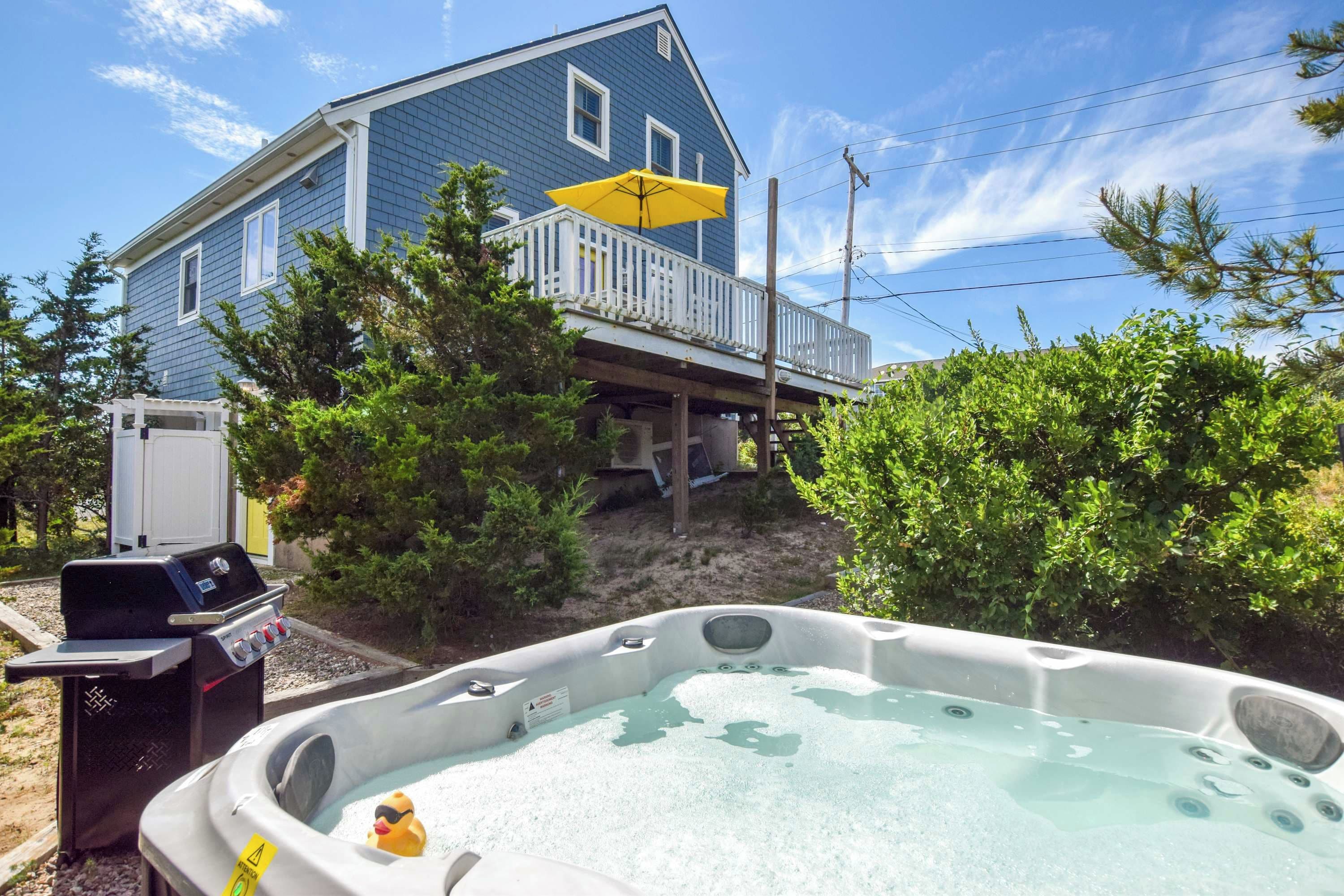 Ein Haus mit Terrasse, einem Whirlpool und einem Grill.