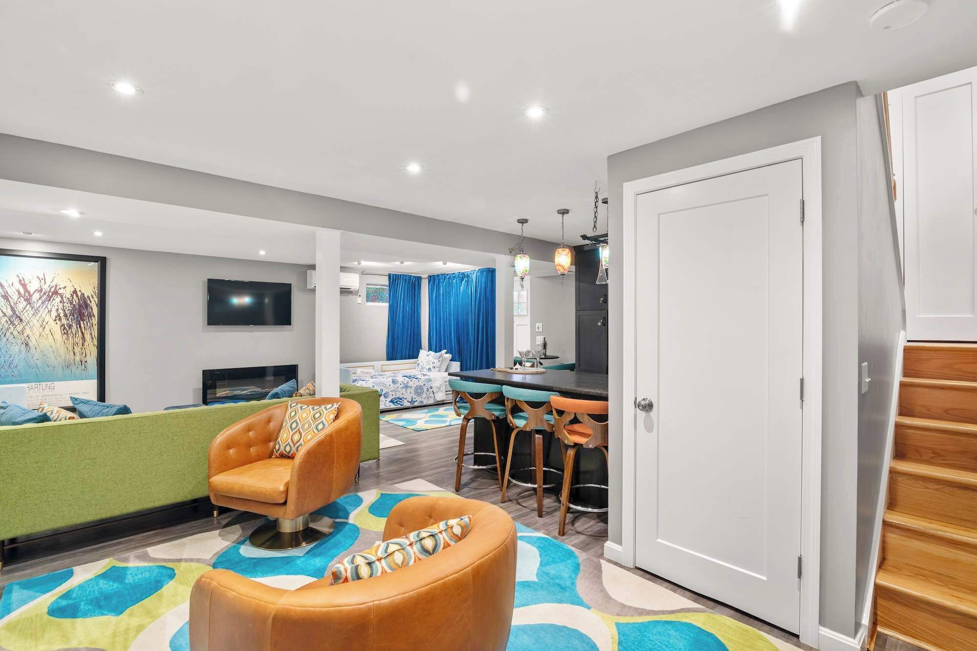 A modern living room with a sofa, ottoman, and a dining area with chairs and a table.