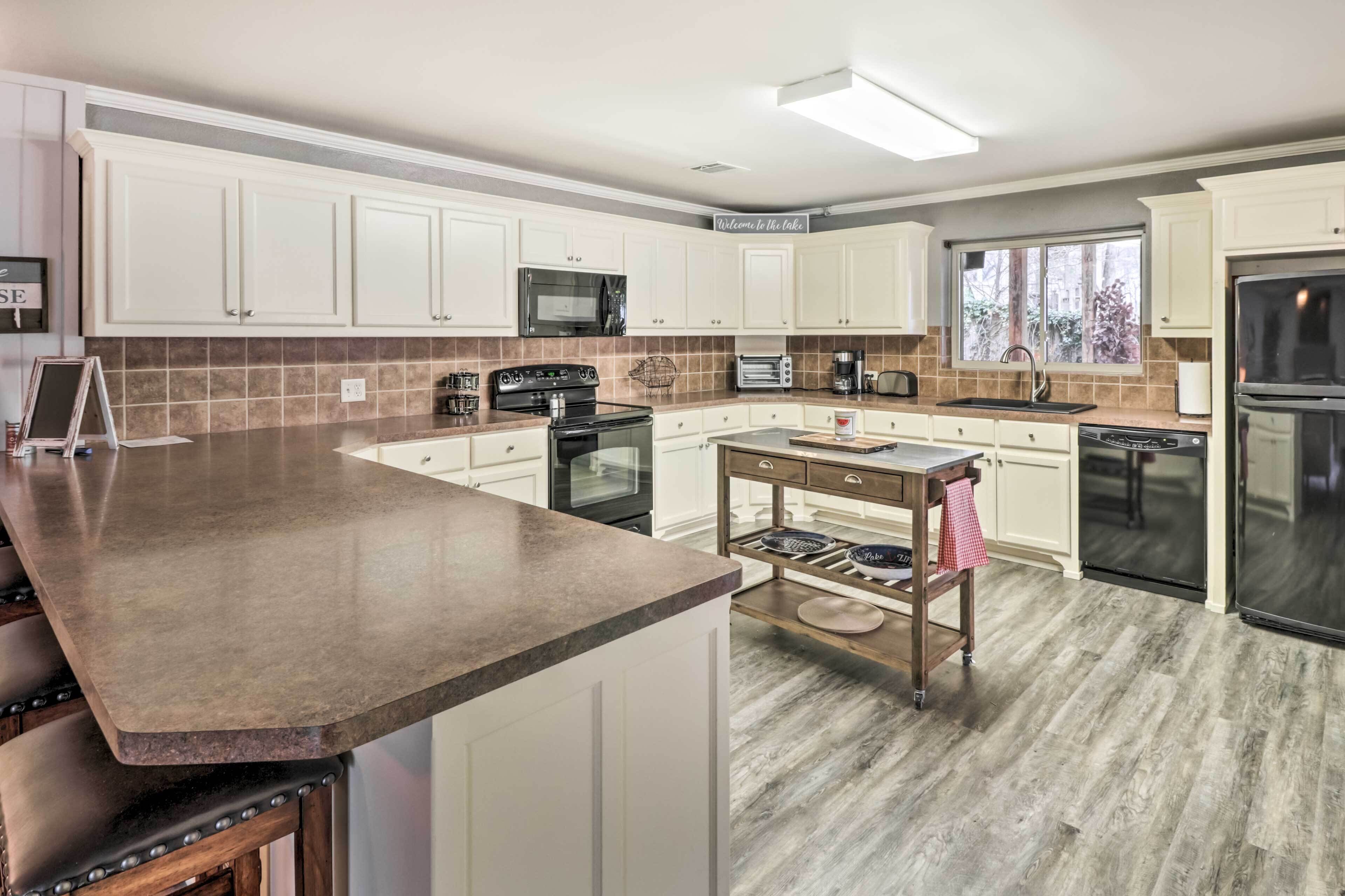 A modern kitchen with white cabinets, a granite countertop, stainless steel appliances, and a window providing natural light.