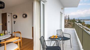 Un balcón con mesa para dos, una silla y vistas al mar y a las montañas.