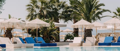 Una piscina al aire libre, sombrillas, sillones reclinables de piscina