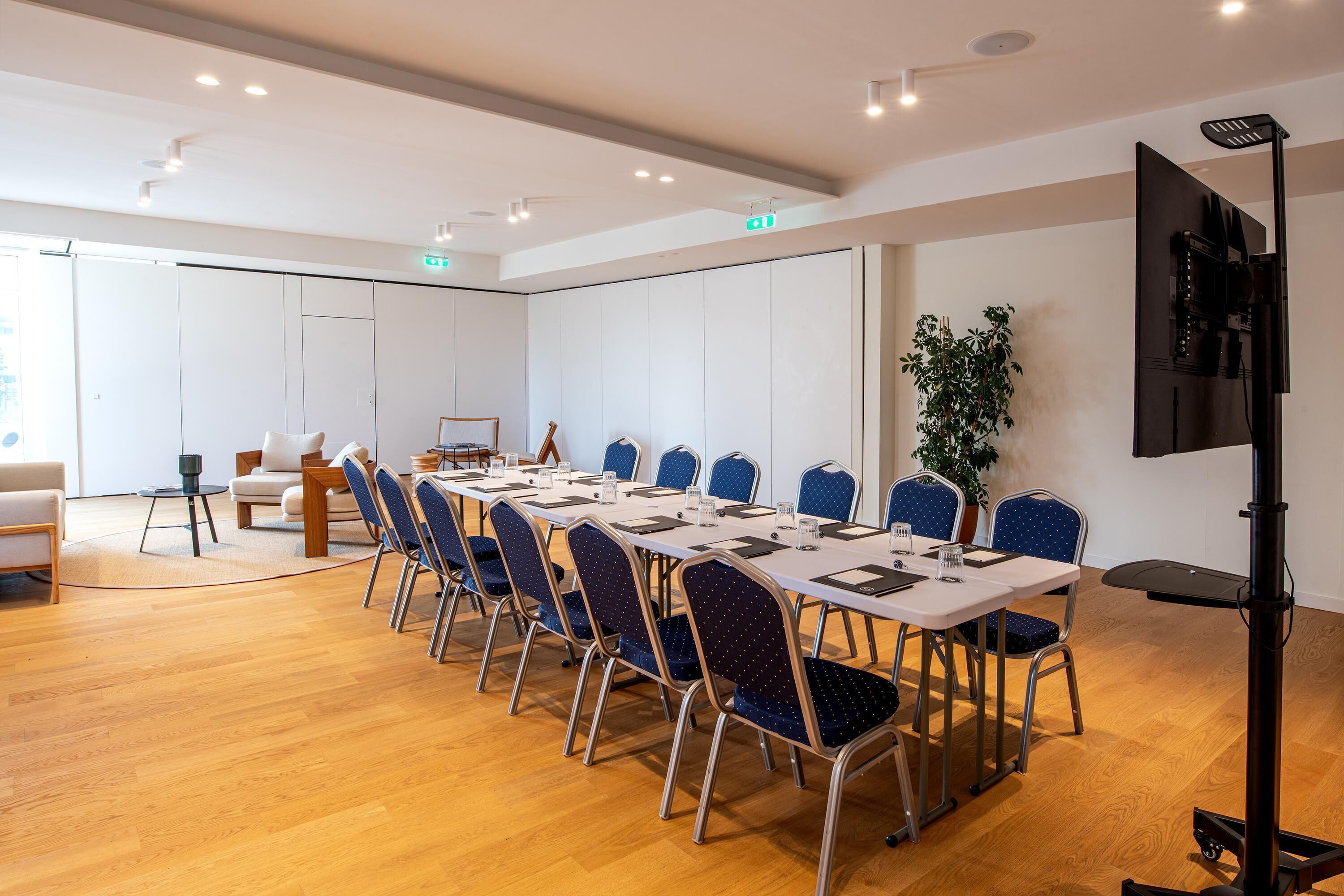 A conference room with a long table, blue chairs, and a projector.