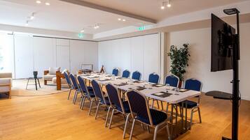 A conference room with a long table, blue chairs, and a projector.