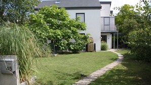 A modern two-story house with a well-maintained lawn and a pathway leading to the entrance.