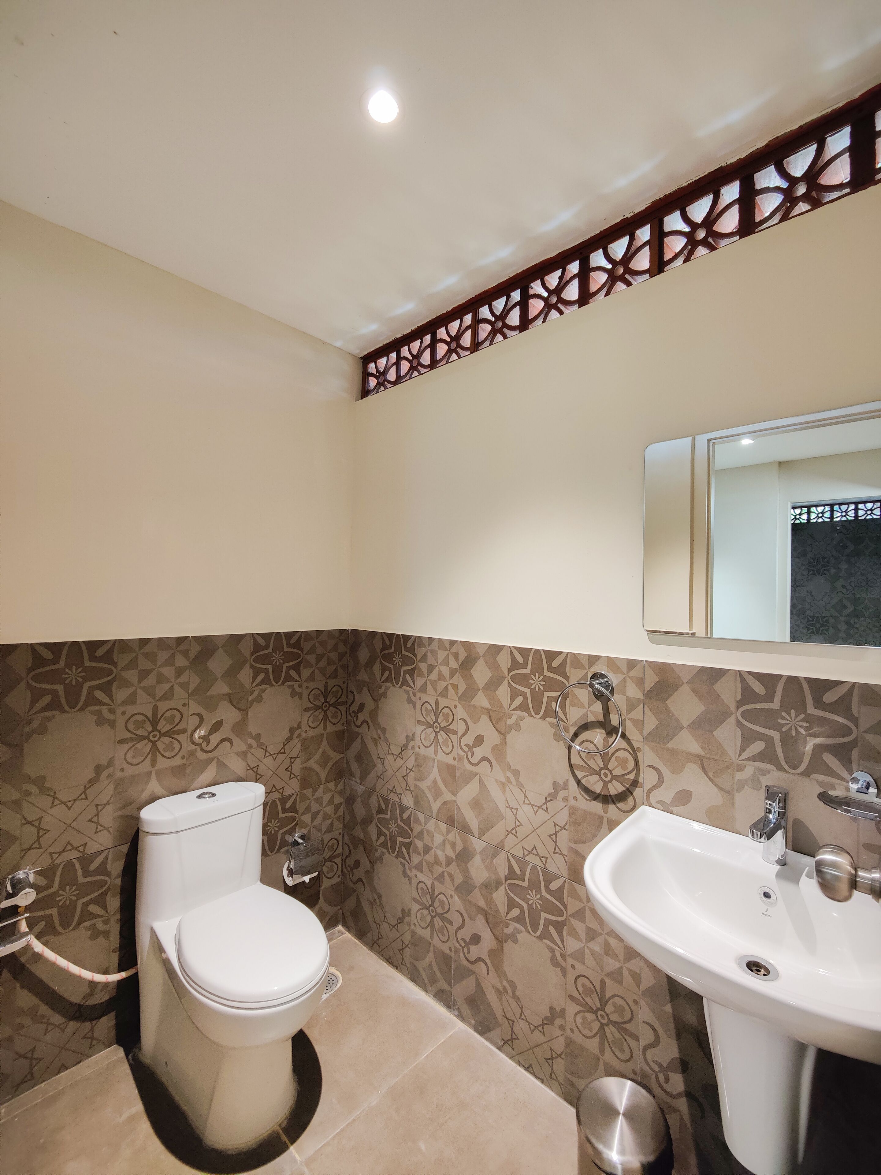 Un baño con inodoro, lavabo y azulejos decorativos.