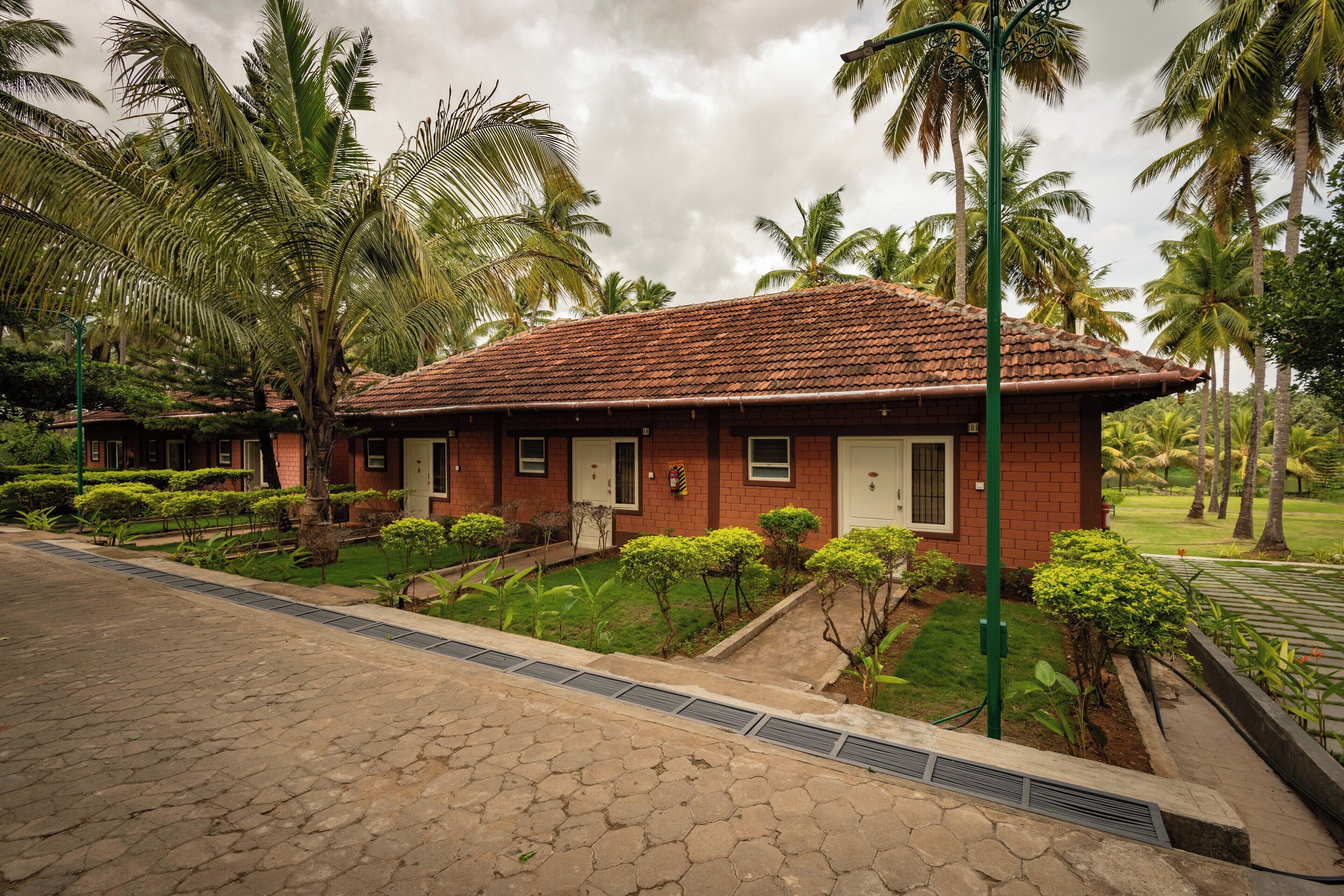 A red-roofed building with a small porch, surrounded by palm trees and well-maintained greenery.