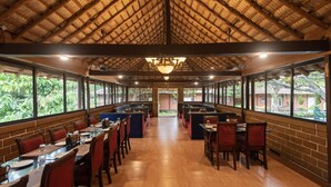 Um restaurante espaçoso com teto alto e luz natural que entra por grandes janelas.