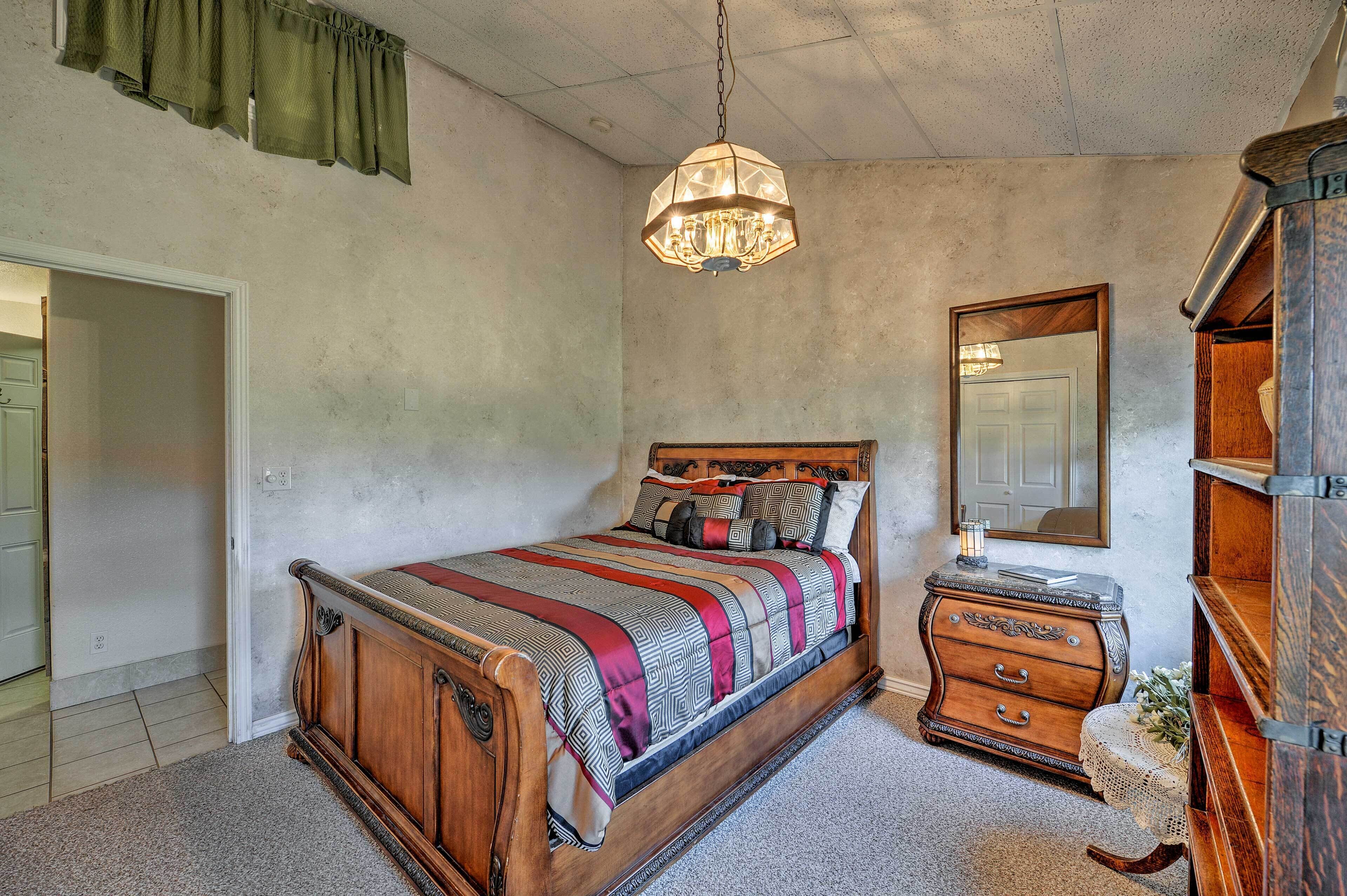 A bedroom with a wooden bed, a dresser, a mirror, and a hanging light fixture.