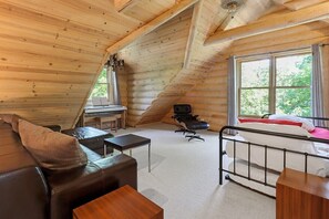 A cozy log cabin room with a loft bed, a leather sofa, a small desk, and a chair. - Renovated Log Home At Lake Geneva |Game Room |Ping Pong |Shuffleboard |Movie Room |Swingset |FirePit (Fontana)
