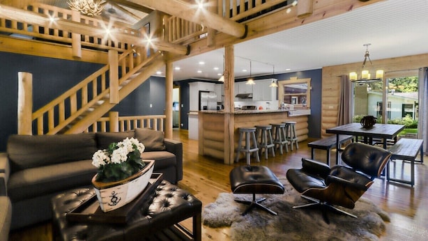 Un interior moderno con una escalera de madera, una zona de cocina y un espacio para comer.