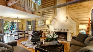 Interior de una cabaña de troncos con chimenea, muebles de madera y un comedor.