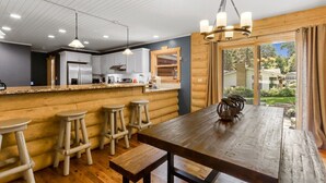 Una cocina rústica con detalles de madera, una amplia mesa de madera y taburetes de bar.