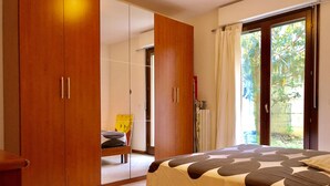 A bedroom with a bed, a wooden wardrobe, a chair, and a sliding glass door leading to a balcony. - Terrace overlooking the sea and Marche hills (Grottammare)
