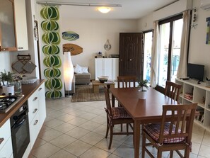 A modern kitchen with a dining area, featuring a wooden table, chairs, and a view of the outside.
