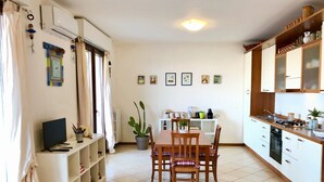 A modern kitchen with white cabinets, a dining table with chairs, and a small dining area. - Terrace overlooking the sea and Marche hills (Grottammare)
