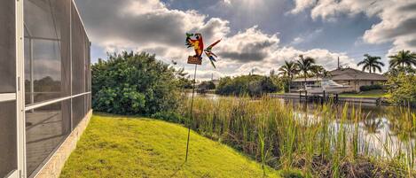 A modern building with large windows, a grassy area, a pond, and a kite flying in the sky.