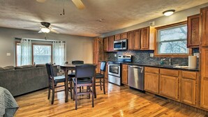 A modern kitchen with wooden cabinets, a dining area with a table and chairs, and a ceiling fan. - Stockton Lake Escape w/ Kitchen, Half Mile to Lake (Stockton)