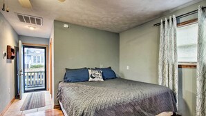 A bedroom with a bed, a door leading to a balcony, and a window with curtains. - Stockton Lake Escape w/ Kitchen, Half Mile to Lake (Stockton)