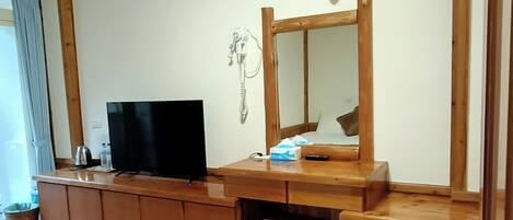 A wooden-framed room with a flat-screen TV, a mirror, and a small stool.