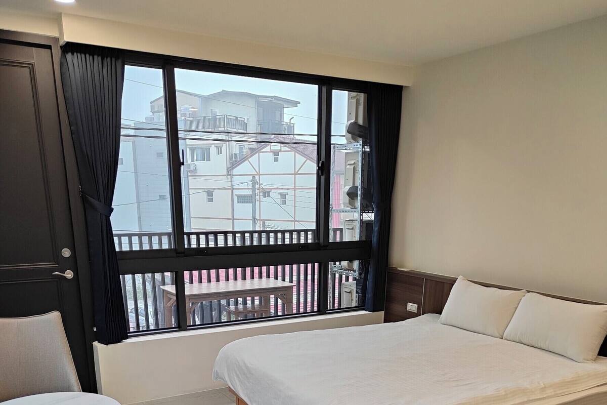 A hotel room with a large bed, a small round table, and a chair.