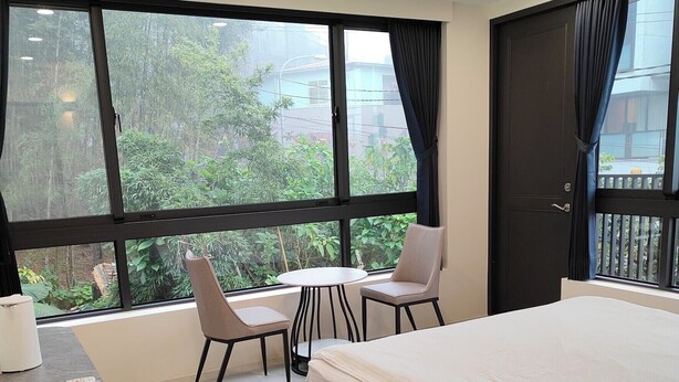 A hotel room with a large bed, two chairs, a small table, and a desk with a remote control and books. - Tian Pin Guest House (Lugu)