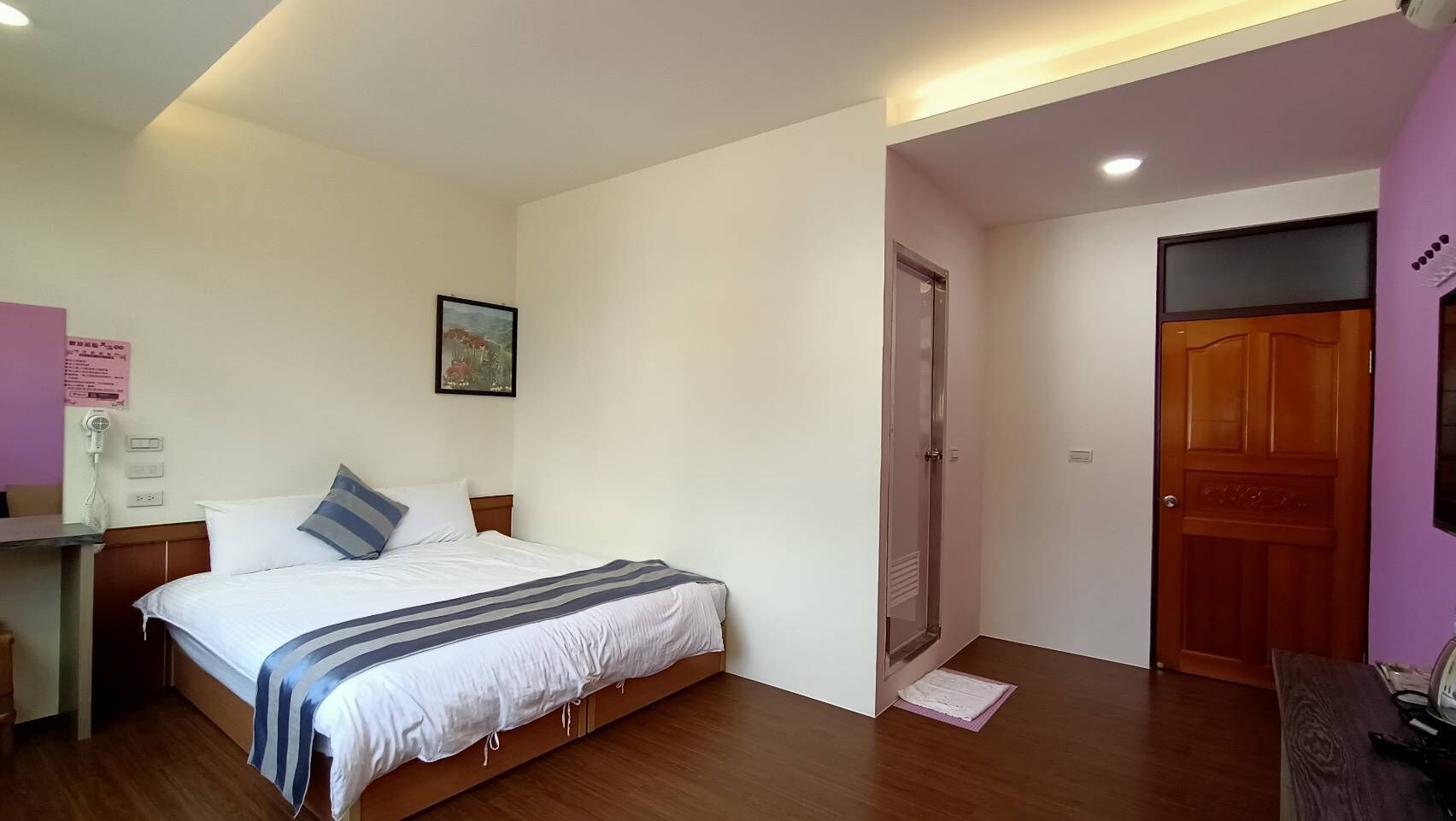 Un dormitorio con cama, mesita de noche y una puerta que da a otra habitación.