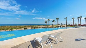 A poolside area with lounge chairs and a view of the ocean.