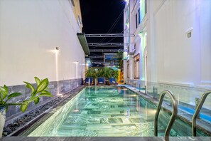 A pool area with clear water, surrounded by walls and plants, and a staircase leading to an upper level. - Gioan Boutique Villa (Da Nang)