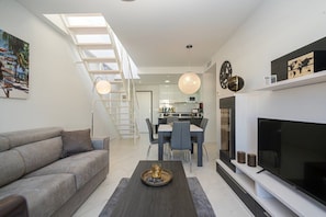 A modern living room with a sofa, coffee table, TV, and dining area. - Apartamento Neptuno (Mar de Pulpi) (San Juan de los terreros)