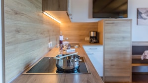 A modern kitchen with a wooden countertop, stainless steel cookware, and a built-in stove.