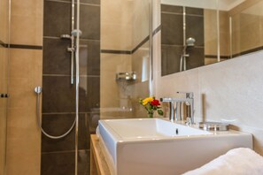 A bathroom with a white sink, a mirror, and a shower.