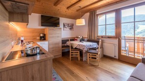 A wooden interior with a kitchen, dining area, and a view through large windows.