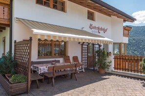 A restaurant with outdoor seating, a wooden fence, and a mountain view.