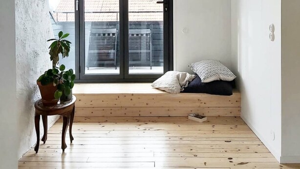 A room with a large sliding glass door, a wooden floor, a small table with a potted plant, and a bed with pillows. - 140 sqm and garden in cozy and city near Kålltorp, also Gothia cup (Kålltorp)