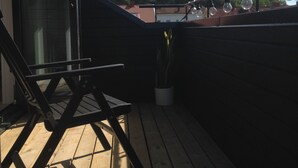 A wooden deck with a glass door leading to a room, a potted plant, and a metal railing. - 140 sqm and garden in cozy and city near Kålltorp, also Gothia cup (Kålltorp)