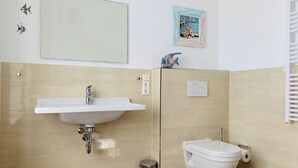 Un baño con lavamanos, inodoro y un cubo de basura.