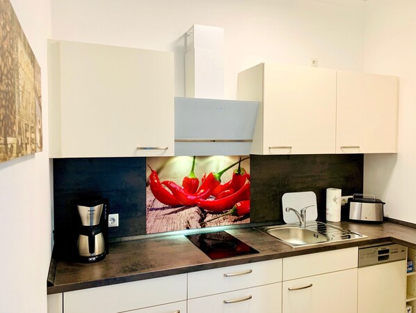 A modern kitchen with white cabinets, a built-in oven, a coffee maker, and a sink.