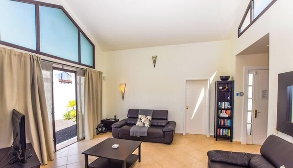 Een ruime woonkamer met een bank, salontafel en een boekenkast.